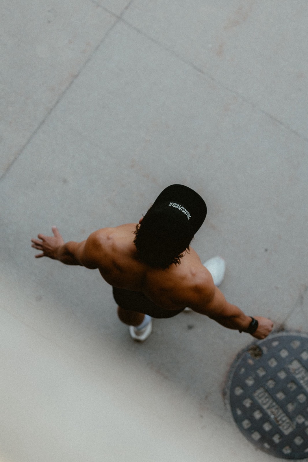 Overhead shot of Logan in a Tmrrw Project cap walking with one arm outstretched
