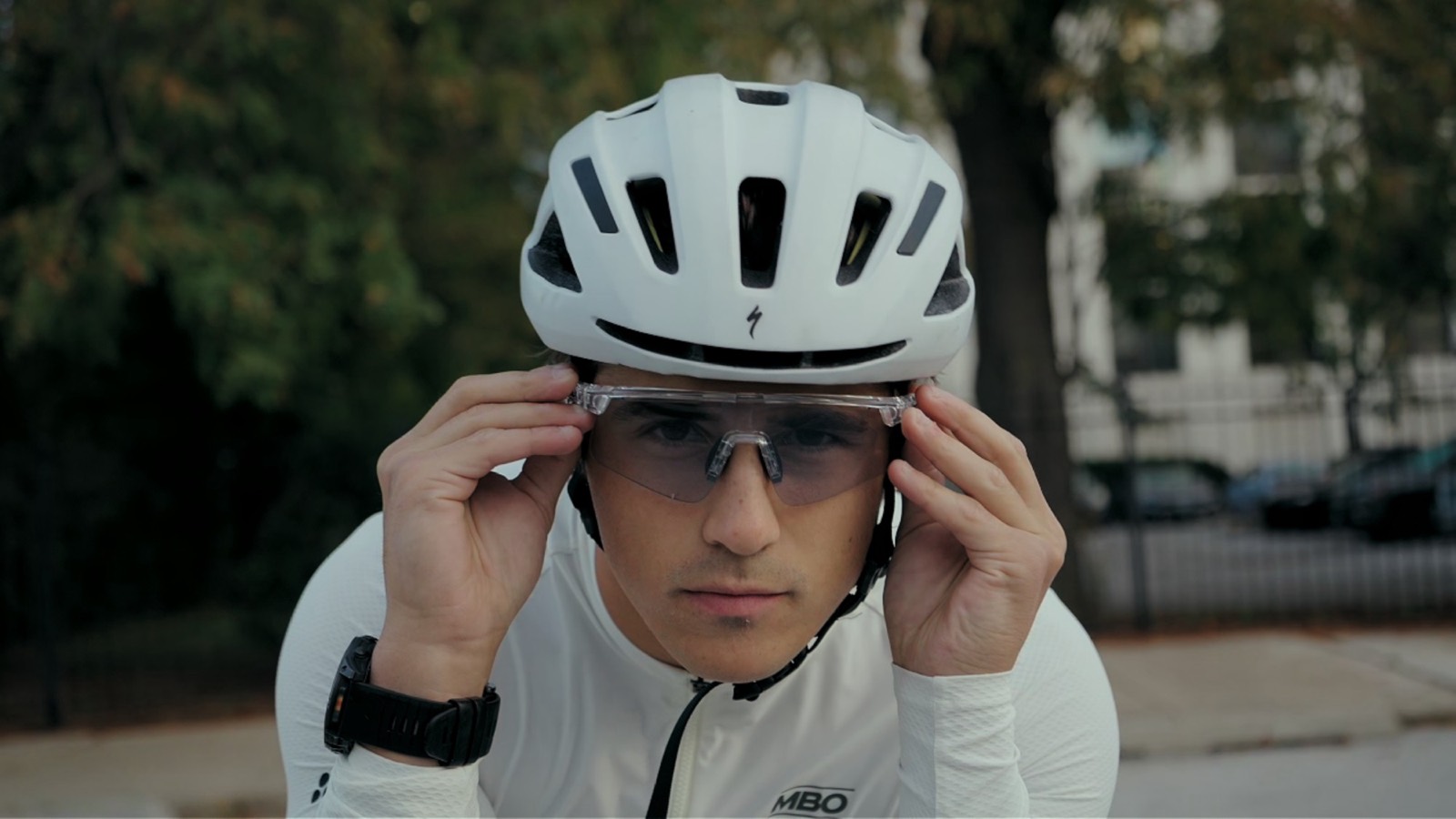 Logan adjusting clear Spekoptics sport sunglasses under a white cycling helmet