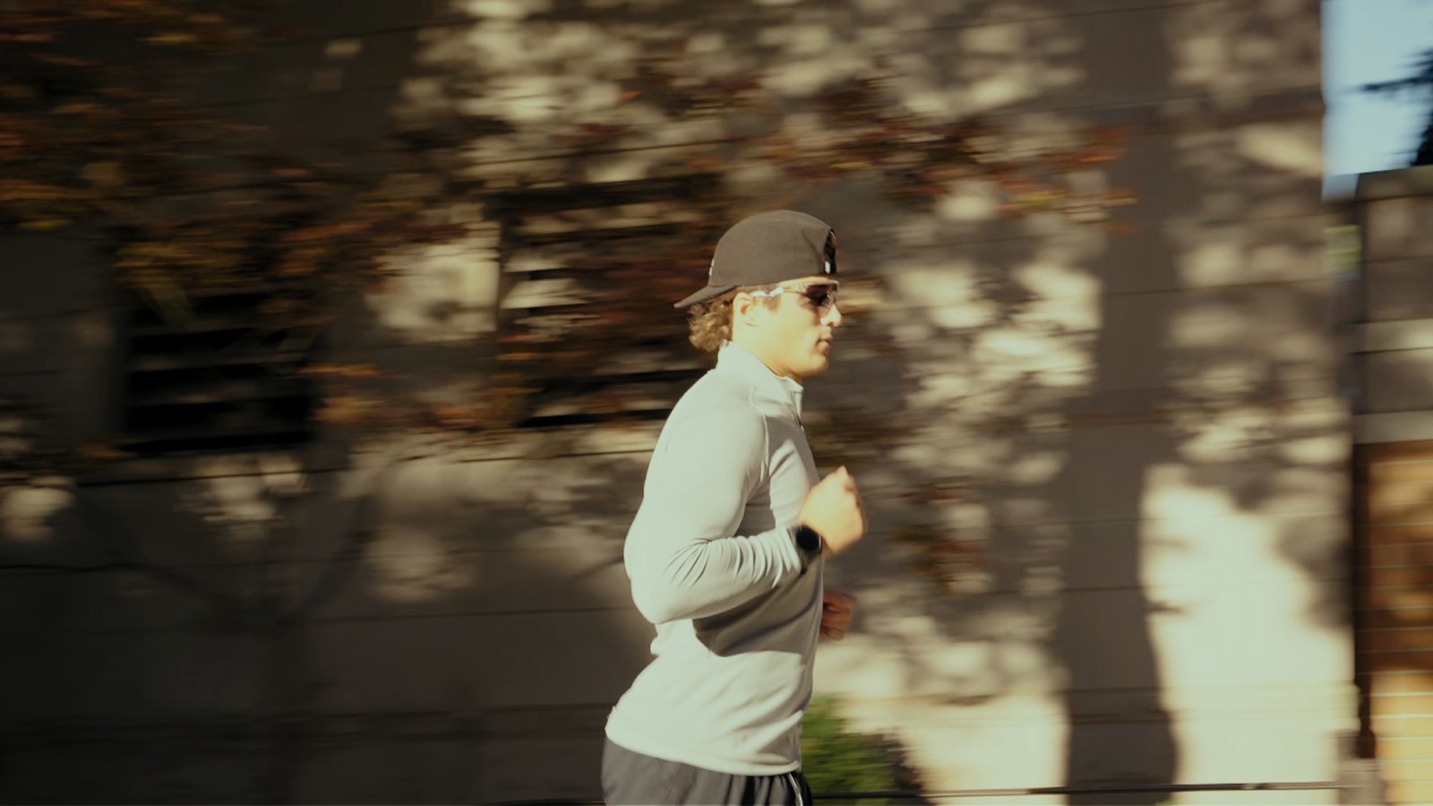 Logan running past a sunlit wall wearing Spekoptics sunglasses